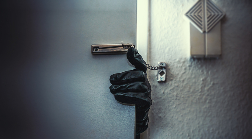 Hand with black glove opening door with chain on it.
